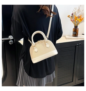 Detail of a chic straw and leather shell bag with gold zippers and adjustable strap