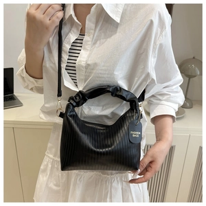 Detail of black pleated bucket bag with textured vertical stripes and adjustable strap