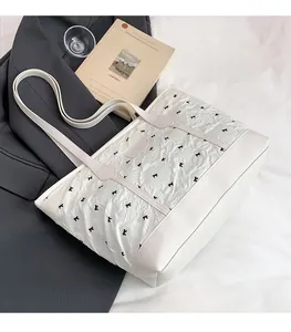 Macro shot of white pleated fabric tote bag with black bow details in a lifestyle setting