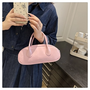 Detail of pink glossy leather handbag showing dual handles and zipper on round shoulder bag