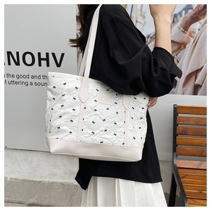 Close-up of white tote bag with black bow prints and durable cream leather bottom detail