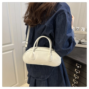 Detail of a creamy white PU leather Boston bag shown from a model's back-side view