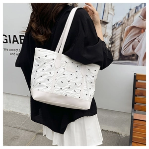 Detail of white tote bag with black bow patterns on textured quilted fabric