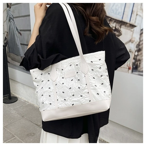 Detail of white quilted tote bag with black bow embroidery and Creative Girl patch
