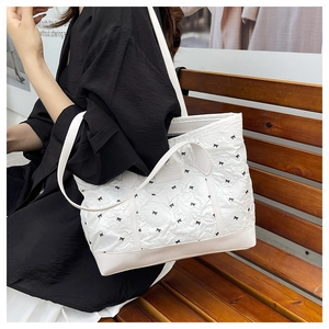 Detail of white quilted tote bag with black bow print and Creative Cat leather patch