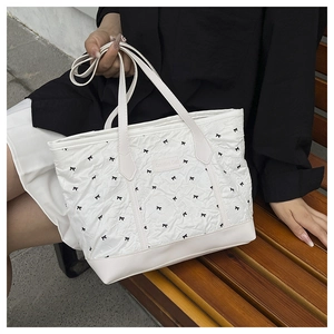 Detail of white tote bag with black bow patterns and a Creative Cat leather label