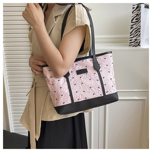 Close-up of pink pleated tote bag with black bow patterns and leather shoulder straps