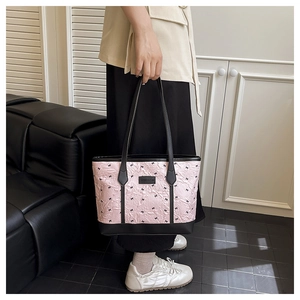 Detail of pink ruffled tote bag with black bows and Creative Cat logo on a shoulder strap