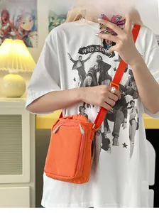 Orange nylon mini crossbody bag shown on model in a casual lifestyle indoor setting
