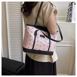 Detail of pink bow-patterned tote bag featuring black leather trim and Creative patch
