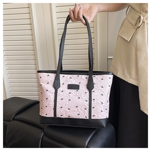 Detail of pink bow-print tote bag with black leather handles and Creative Cat label