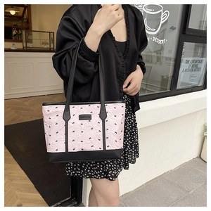 Close-up of pink tote bag with bow prints and Creative Cat label held by a model outdoors