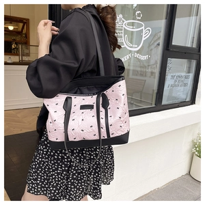 Lifestyle shot of pink tote bag with black bow print and shoulder straps for daily use