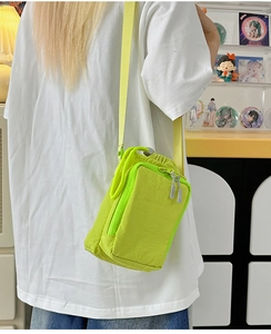 Detail of neon green nylon crossbody phone bag with drawstring and adjustable strap