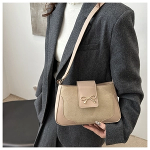 Detail of beige shoulder bag with suede textures and a metallic bow buckle on blazer