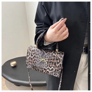 Detail der Handtasche mit Leopardenmuster, goldener Schleife und feiner Lederstruktur
