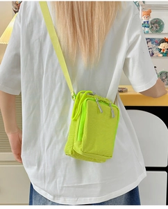 Rear view of a model wearing the neon green mini canvas crossbody bag with adjustable strap