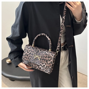 Detail der Leopard-Handtasche mit goldener Schleifenschnalle und strukturierter Oberfläche