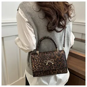 Detailansicht der Damen-Umhängetasche mit Leopardenmuster und goldener Schleife an Model