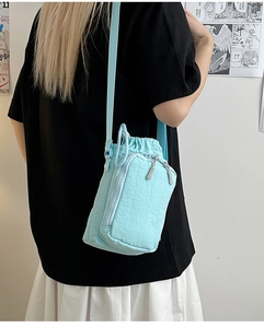 Detail of light blue nylon crossbody bag with drawstring closure and stylish pleated texture