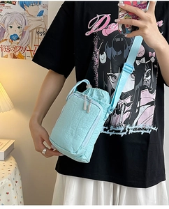 Close-up of light blue nylon crossbody bag with drawstring closure and vertical zipper pocket