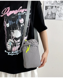 Detail of grey mini nylon crossbody bag with drawstring closure and green zipper tab