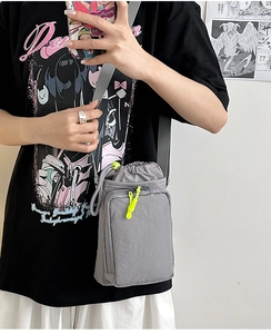 Detailed view of gray nylon crossbody bag with drawstring closure and neon zipper accents