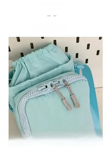 Close-up of light blue textured nylon crossbody bag featuring dual gray smooth zippers