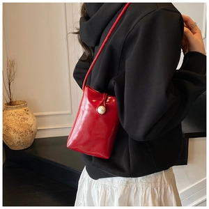 Red glossy leather mini crossbody phone bag with pearl clasp decoration on model