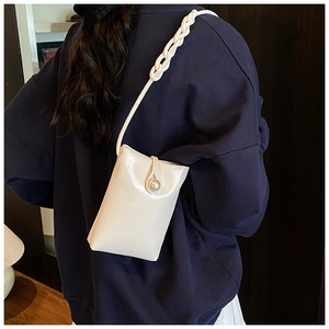 Close-up of stylish mini crossbody bag with pearl clasp and woven chain strap detail