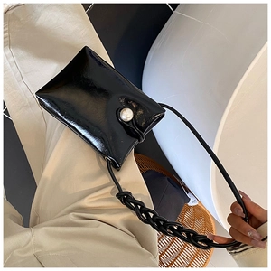 Detail of glossy black mini shoulder bag with large pearl buckle and woven rope strap