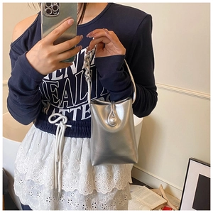 Detail of silver metallic mini crossbody bag with twisted handle and round accent