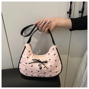 Détail du sac hobo plissé rose avec nœud noir et pendentif en forme de cœur argent