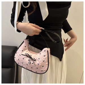 Detail of pink crescent bag with black bows, silver heart charm and shoulder strap