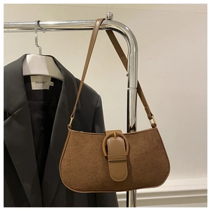 Detail einer Vintage-Schultertasche aus braunem Wildleder mit großer goldener Hufeisenschnalle