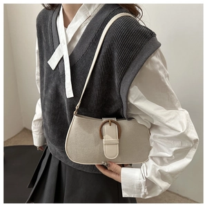 Close-up of minimalist beige suede underarm bag with retro circular ring buckle detail