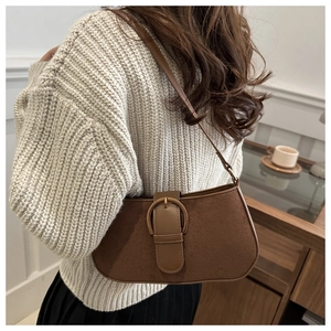 Detail view of large dark brown matte shoulder bag with vintage bronze buckle on model