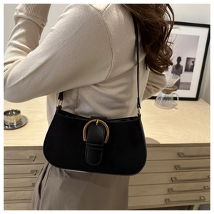 Detail of a vintage black underarm bag with golden horseshoe buckle in home setting