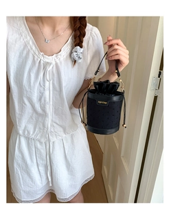 Close-up of black bucket bag with satin drawstring and gold jingpin logo branding