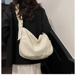 Detail of minimalist cream canvas hobo bag with wide shoulder strap on model's shoulder