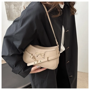 Mannequin portant un sac baguette vintage beige avec boucle nœud doré et œillets