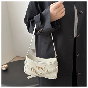 Vue détaillée d'un sac à bandoulière beige avec nœud métallique et lanière décorative