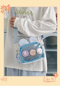 Detail of light blue rabbit ear bag with clear pocket and decorative happy badges