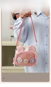 Detail view of pink rabbit-ear crossbody bag with grid pocket and cartoon badges