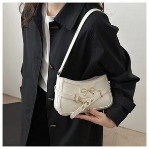Détail du sac à bandoulière blanc crème avec nœud en métal doré et brides croisées