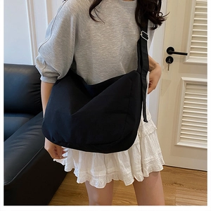 Minimalist large black canvas tote bag with wide adjustable shoulder strap on a model