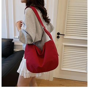 Detail view of large red canvas hobo bag with wide adjustable shoulder strap on a model