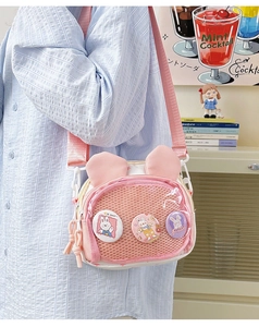 Detail shot of cute bunny ear crossbody bag with decorative badges and mesh pocket design