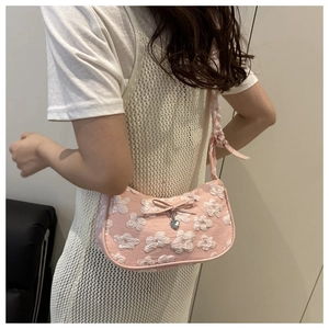 Detalle del bolso rosa fruncido con textura floral 3D y colgante de corazón metálico
