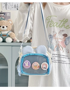 Detail of light blue crossbody bag with mesh pocket and cute rabbit badges for students